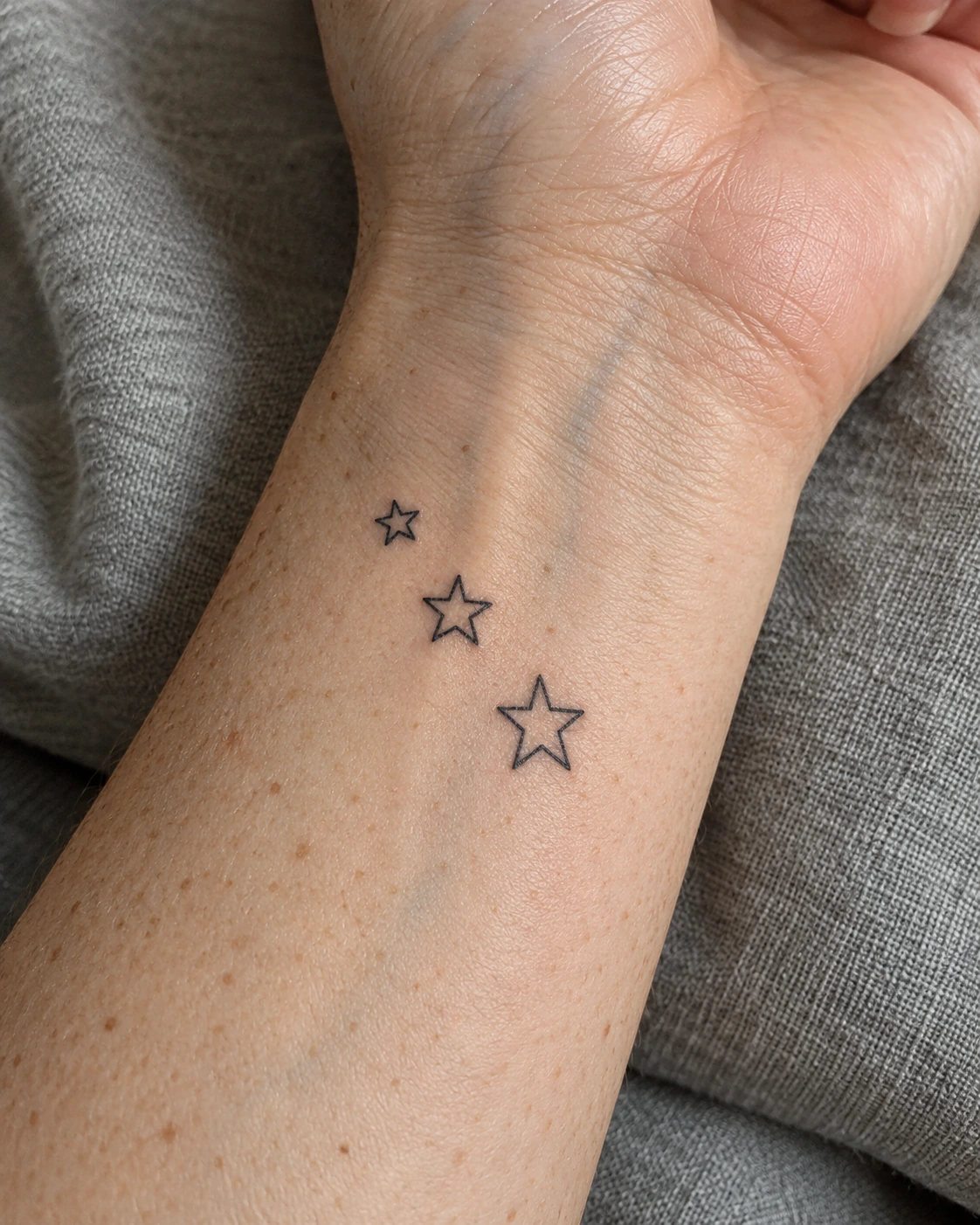 Tatouage étoile : repère, souvenir ou vœu, choisir le bon motif | TATOUEZ Trois petites étoiles à cinq pointes de tailles différentes sur un poignet.